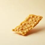 Single piece of golden peanut brittle on a light background.